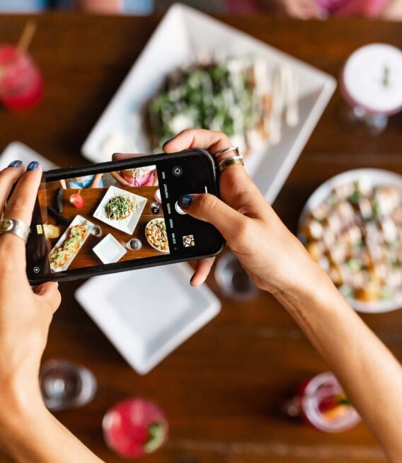 A UF student holding an iPhone over the table at Oak Gainesville to take an aerial photo of her brunch