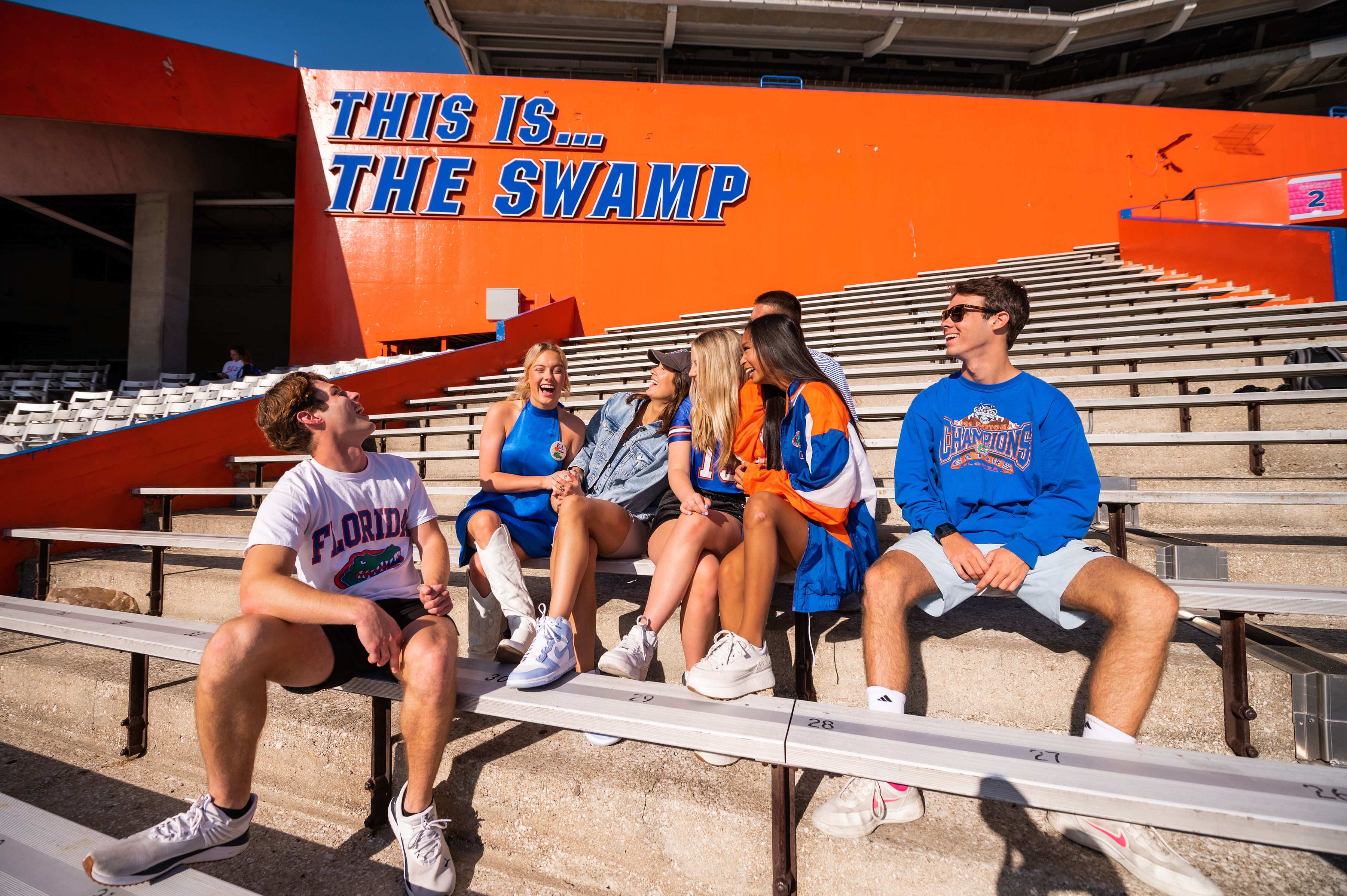 six UF students sit in the bleachers in front of the "this is... the swamp" sign in UF's football stadium in Gainesville, Florida