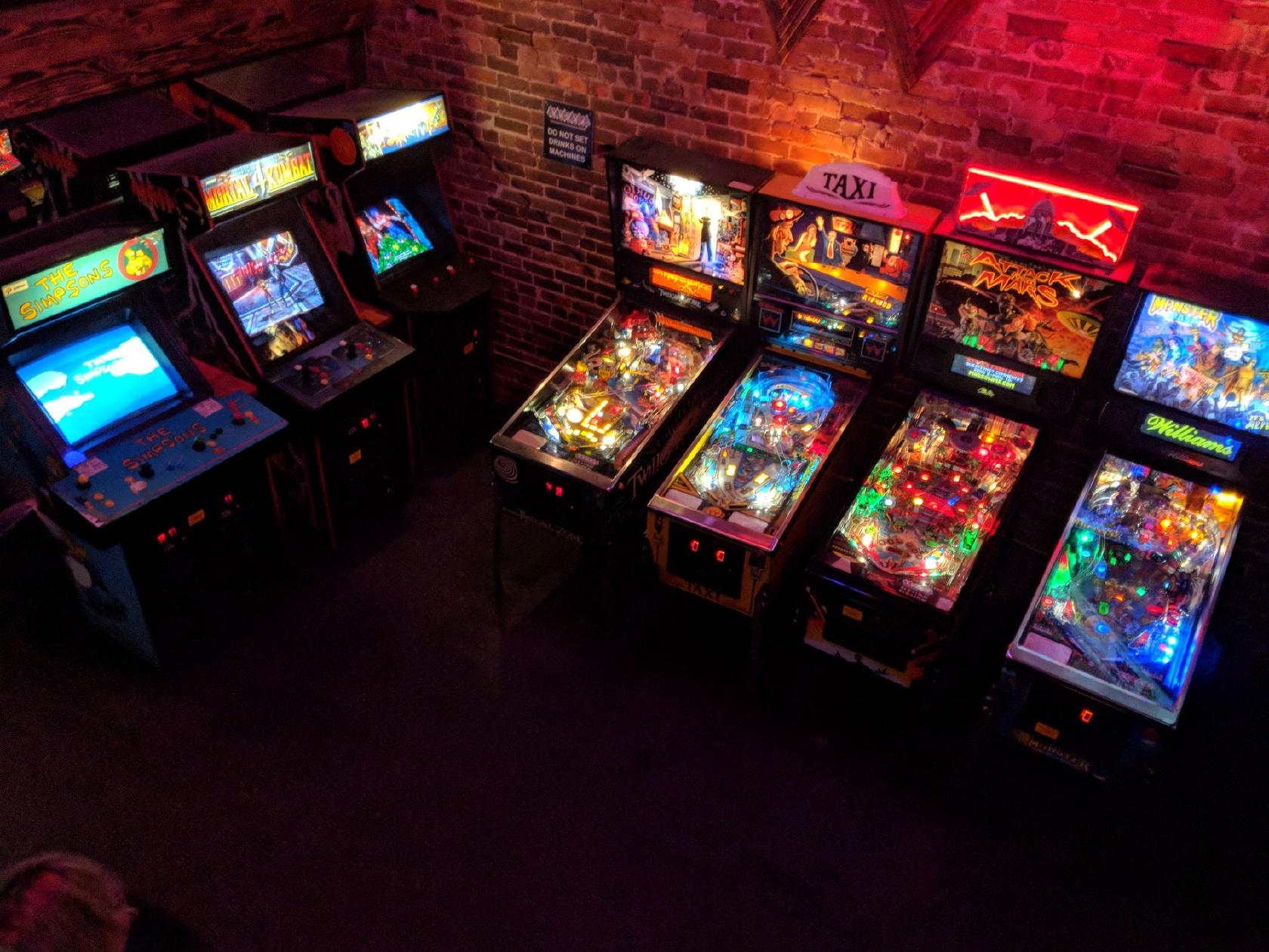 seven retro gaming machines like mortal kombat line the wall of arcade bar, or barcade, in gainesville florida