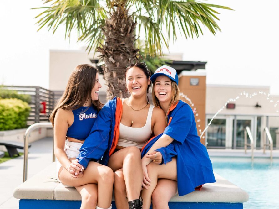 Three roommates at the University of Florida in Gainesville laugh together at Sweetwater while sitting at their apartment's rooftop pool