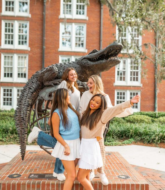four girls hug in front of the gator statue at UF